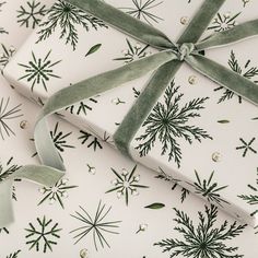 wrapping paper wrapped in green and white with snowflakes on it, as well as a ribbon