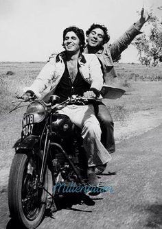 two women riding on the back of a motorcycle down a road with their arms in the air