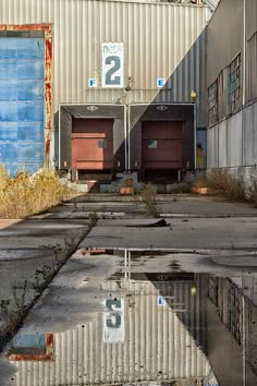 an abandoned industrial building with water reflecting off the ground and two doors on each side