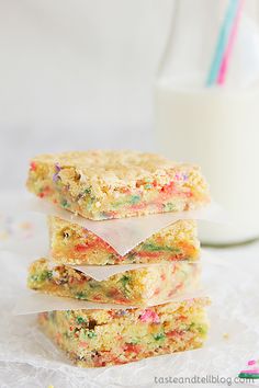 three pieces of cake sitting on top of a table next to a glass of milk