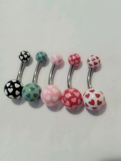 four different colored polka dot and heart shaped belly rings