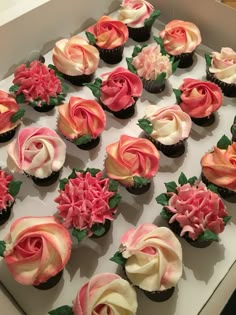 a box filled with cupcakes covered in pink and white frosting flowers on top of each other