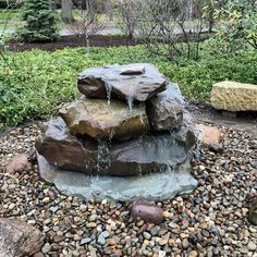 a rock fountain in the middle of a garden