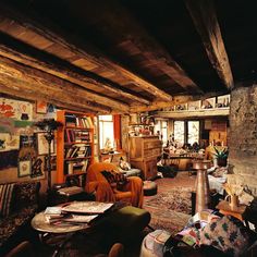 a living room filled with lots of furniture and bookshelves next to a fire place