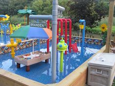 the children's play area has an umbrella, sandbox and water toys in it