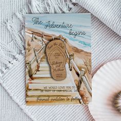 a card with the words'the adventure begins'on it next to a seashell