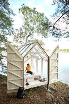 a person sitting on top of a bed in a wooden structure next to a body of water