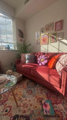 a living room with a red couch and colorful rugs on the floor in front of a window