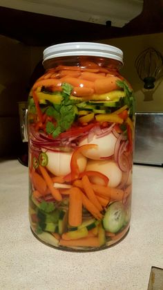 a glass jar filled with sliced vegetables on top of a counter