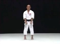 a man standing on top of a white floor holding a black belt