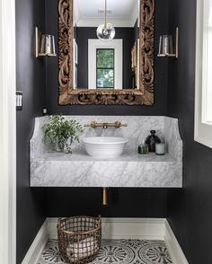 a white sink sitting under a mirror next to a bathroom vanity with a gold framed mirror above it