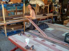 a man standing next to a wooden table in a shop with tools and materials on it