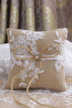 a pillow with a bow tied to it on top of a white lace covered bed