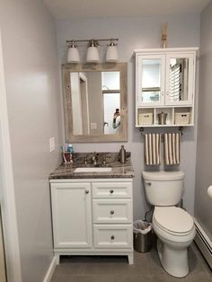 a white toilet sitting next to a sink in a bathroom under a mirror and lights