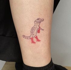 a small lizard tattoo on the leg of a woman's leg with red heels