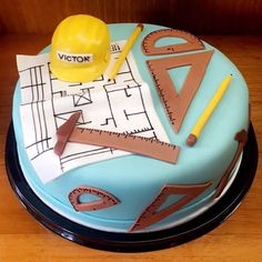 a cake with construction themed frosting on it's side, including a hard hat and ruler