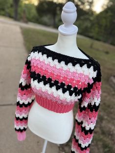 a white mannequin wearing a pink and black sweater