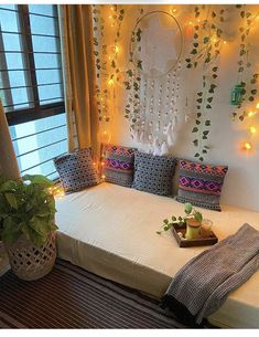 a white bed sitting under a window next to a potted plant