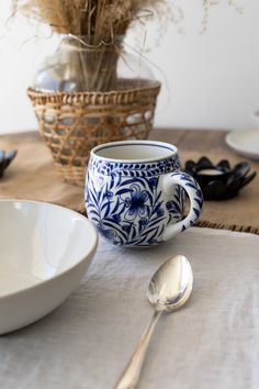 a blue and white coffee cup sitting on top of a table next to a bowl