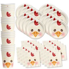 a bunch of white plates and cups with red rooster faces on them, sitting next to each other