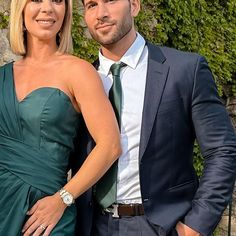 a man and woman in formal wear standing next to each other near a stone wall