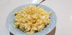 a blue bowl filled with macaroni and cheese on top of a white counter