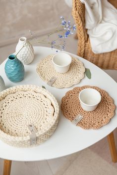 the table is set with crocheted placemats and cups, along with two vases