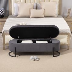 an open suitcase sitting on the floor in front of a bed with pillows and slippers