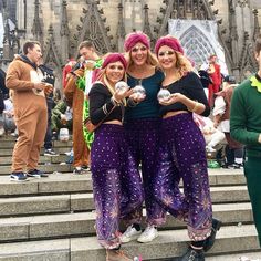 three women in purple pants are standing on the steps with their arms around each other