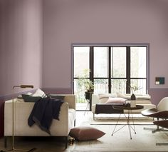 a living room with purple walls and furniture in the center, along with a large window