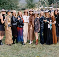 a group of women standing next to each other on top of a grass covered field