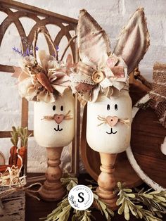 two white painted eggs with bunny ears and bows on them sitting next to each other