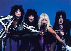 the band kiss posing for a photo in front of a blue background with their guitars