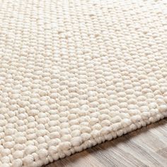 a white rug on top of a wooden floor next to a wood flooring board