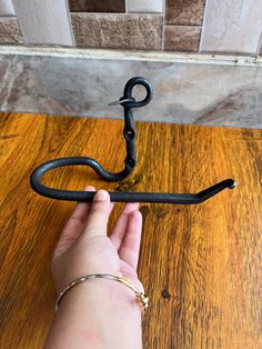 a person is holding an old hook on a wooden table