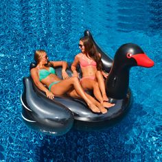 two women in bikinis sitting on an inflatable duck