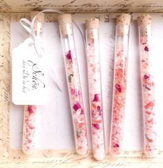 four pink and white floral pens in a wooden box with tags on the top of them