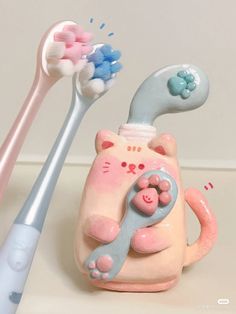 two toothbrushes and a cat figurine sitting on a counter next to each other