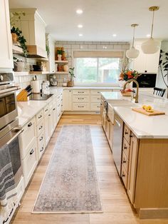 a large kitchen with white cabinets and wooden flooring, along with an area rug