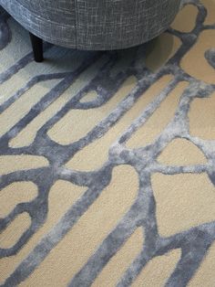 a grey and yellow rug on the floor next to a gray chair with black legs