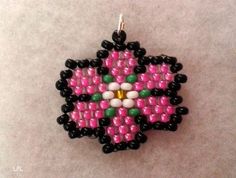 a pink and black beaded ornament hanging from a hook on a white surface