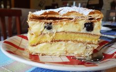 a piece of cake with blueberries and powdered sugar sits on a plate next to a fork