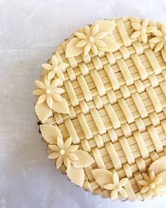 a pie that is sitting on top of a white tablecloth with flowers in the middle