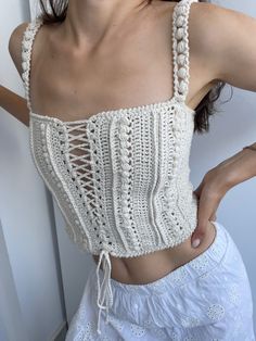 a woman wearing a white crochet crop top with an attached tie around her waist