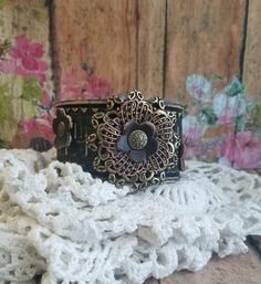 "BOHO CHIC statement bracelet to wear with your favorite outfit ❤ Looks beautiful alone or layered for a UNIQUE look! This DESIGN features: ❤ A triple layer flower comprised of metal flower filigrees in bronze and copper and topped by an adorable tiny leather flower. ❤ Handpainted black tooled leather cuff was distressed for a rustic look. ❤ Additional leather flowers border the center piece and were secured with rivets. ❤ The width of the cuff is approximately 1 1/2\" wide. BRACELET SIZING INFO Adjustable Brown Metal Cuff Bracelet, Bohemian Brown Metal Cuff Bracelet, Adjustable Bohemian Flower Cuff Bracelet, Bohemian Adjustable Flower Cuff Bracelet, Elegant Adjustable Cuff Bracelet With Patina, Elegant Adjustable Patina Cuff Bracelet, Vintage Bronze Cuff Bracelet For Festival, Adjustable Copper Flower Jewelry, Brown Metal Bracelets For Festivals