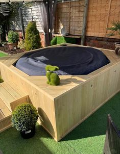 an above ground pool in a backyard with wooden decking and green plants around it