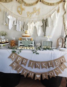 a table topped with lots of food and desserts next to bunting banners that say sprinkled with love