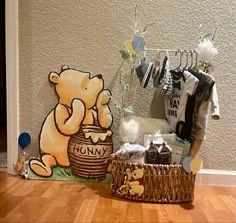 a winnie the pooh wall hanging next to a basket filled with baby items on a wooden floor