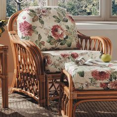 a wicker chair and foot stool in front of a window with flowers on it