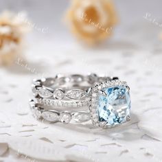 an aqua blue stone surrounded by white diamonds on top of a lace covered table cloth